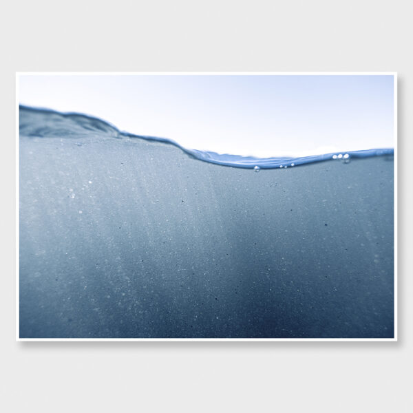 Minimal underwater ocean photograph with suspended particles drifting beneath the surface in soft blue light, creating a calm and immersive seascape fine art print.